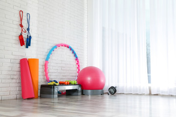 Different sports equipment near white brick wall in gym. Space for text