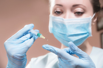 A professional cosmetologist doctor holds in his hand a syringe with anti-aging fluid. A hanging...