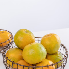 Beautiful peeled tangerines in a plate and metal basket isolated on bright white clean table in a modern contemporary kitchen island, close up.