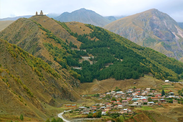 Fototapeta na wymiar Village of Stepantsminda with the curvy road up to the famous Gergeti Trinity Church, Caucasus, Georgia