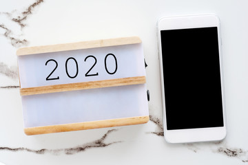 2020 on wood box  and smart phone with blank screen on white marble background, new year communication technology, 2020 mock up, template, banner, background