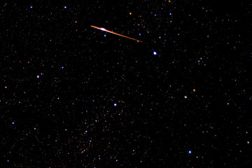 photograph of satellite or shooting star as it passes over deep sky