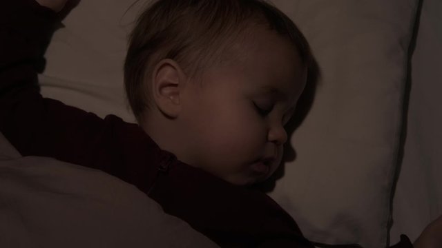 Top view and close-up face of sleeping little cute baby child lying with closed eyes in his bed