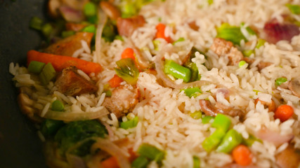 Cooking rice with meat and vegetables, closeup. Culinary background, gastronomy, Asian and Oriental cuisine. Thailand