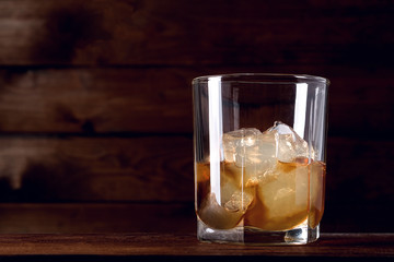 Alcoholic drink, scotch whiskey with ice in a glass of a bartender on a wooden table