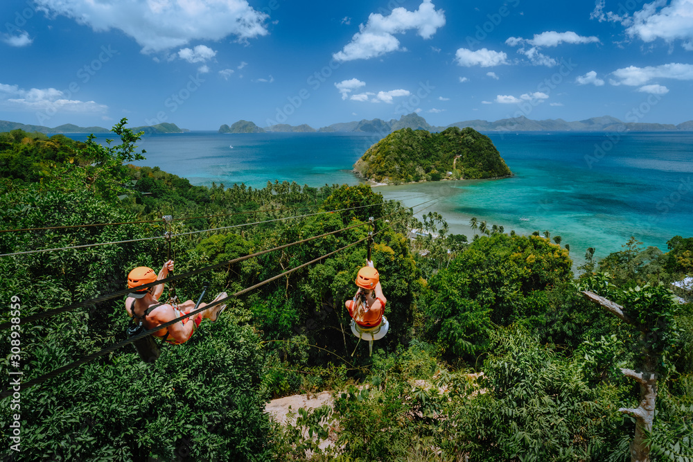 Wall mural zipline over las cabanas beach with tourist on sunny day with white clouds over sea. el nido, palawa