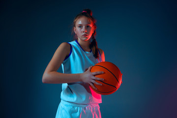Strength.Young caucasian female basketball player on blue studio background in neon light, motion...