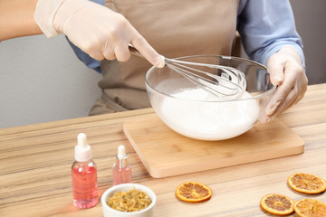 Woman making natural handmade soap at wooden table, closeup