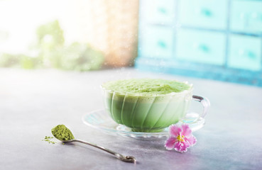 Hot Matcha green tea latte in a cup on a light background. Fashionable energy tea.
