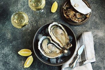 Giant fresh uncooked oysters in a shell with lemon on ice. Healthly food.