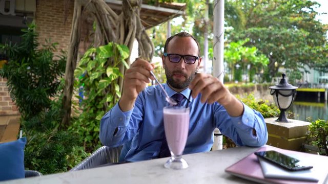 Young businessman relaxing and drinking fresh fruit smoothie cocktail in cafe