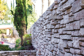 Fototapeta na wymiar Stunning brick wall of Jerusalem stones in the beautiful garden near Herzl's cemetery. Jerusalem, Israel.
