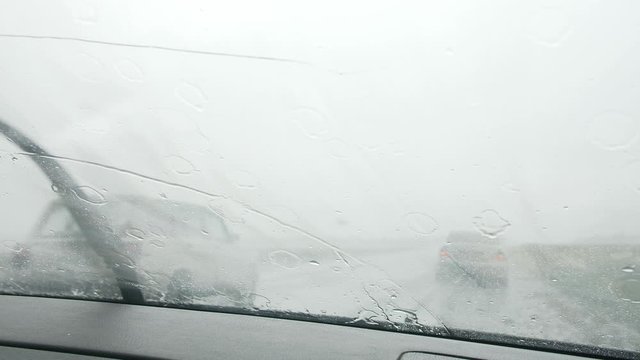 View from the window of the car with working windshield wipers in the rain