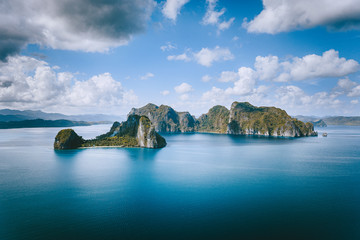 El Nido, Palawan, Philippines. Panoramic aerial view lonely tourist boat in open sea with exotic tropical Pinagbuyutan island standing out in ocean. Southeast Asia Bacuit archipelago