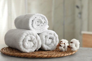 Fototapeta na wymiar Clean rolled towels and cotton flowers on table in bathroom
