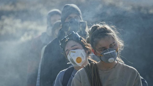 Portrait of people in gas mask standing in clouds of toxic smoke.