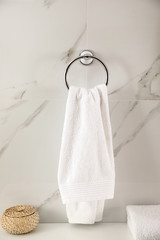 Holder with clean towel on light wall in bathroom