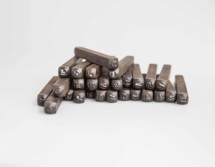 London, England, 29/11/19 vintage retro old school aged wooden box full of a set of alphabetical and numerical steel punches made of strong metal for industrial production shot on white background