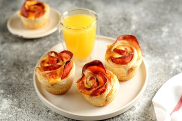 Muffins roses from puff pastry with ham and cheese on a light background.