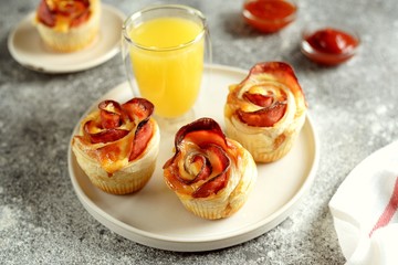 Muffins roses from puff pastry with ham and cheese on a light background.