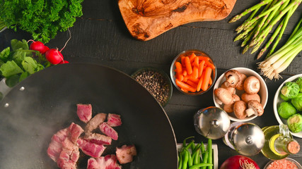 Roasting fresh meat in a wok, on a background with vegetables