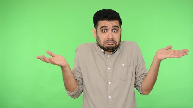 I don't know. Confused brunette man with bristle in shirt shrugging shoulders making questioning gesture, looking uncertain doubtful about answer. indoor studio shot, green background, chroma key