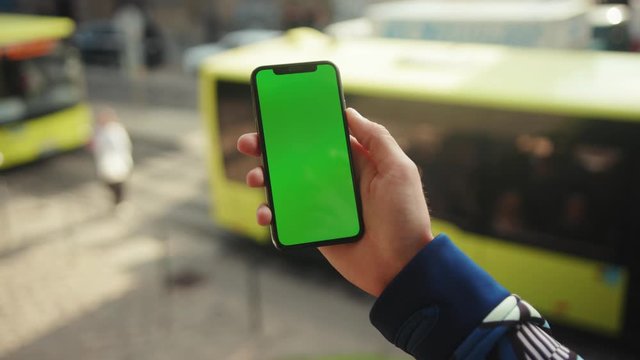 NEW YORK - May 19, 2019: At sunlight hand man using phone with vertical green screen background car city blurred internet chrome outdoor cellular smartphone scrolling tapping communication close up