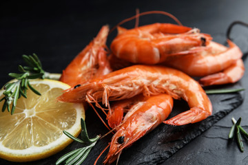 Delicious cooked shrimps with lemon and rosemary on black table, closeup