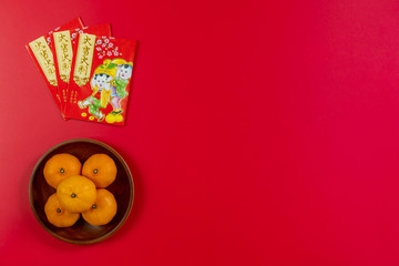Chinese new year festival decorations.,  Red packet and oranges on a red background with copy space for text. Chinese characters is means refer to fortune, wealth, rich, successful.