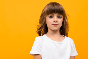 girl with bangs in a white t-shirt on a yellow background close-up