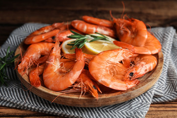 Delicious cooked shrimps with rosemary and lemon on wooden plate