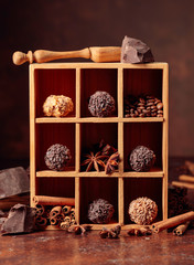 Chocolate truffles with broken pieces of chocolate and spices in wooden box.