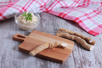 The process of making spicy horseradish sauce. Horseradish root on a cutting board