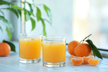 Glasses of fresh tangerine juice and fruits on white wooden table