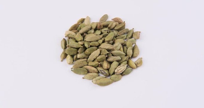 Pile of green cardamom, (dried fruits of Elettaria cardamomum) on white background rotation 360
