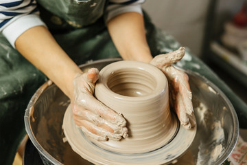 Hands of potter making clay pot on potter's wheel