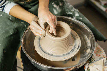 Hands of potter making clay pot on potter's wheel