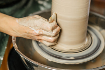 Hands of potter making clay pot on potter's wheel