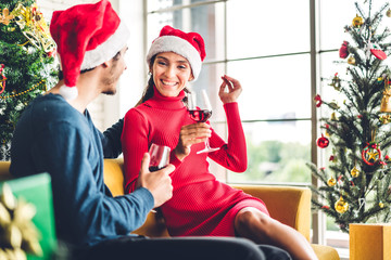 Romantic sweet couple in santa hats having fun and drinking wine glasses while celebrating new year...