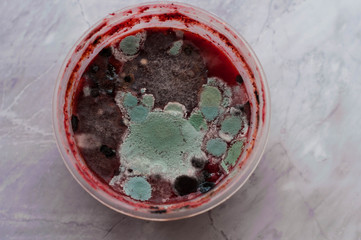 top view of red moldy smoothie in plastik bowl on marble background