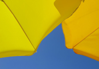 two yellow sun umbrellas blue sky