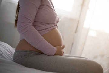 Pregnant woman holding her stomach and relaxing at home.