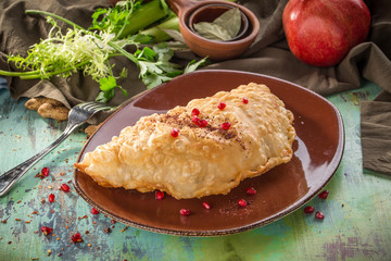 Traditional russian and caucasian meat pie cheburek with pomegranate deep fried on wooden table