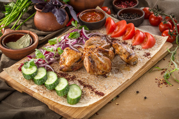chicken shish kebab on lavash bread with red onion, tomato, cucumber and tomato sauce on wooden table