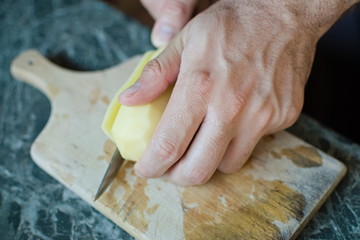 closeup of a hand cutting a potato with a knife