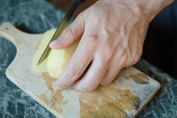 closeup of a hand cutting a potato with a knife