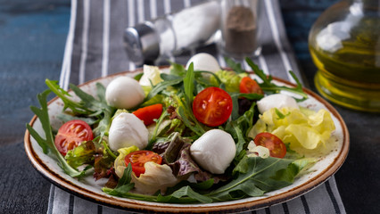 Vegetarian salad with  tomato, arugula, lettuce and mozzarella cheese on a plate. Healthy and diet food. Concept food