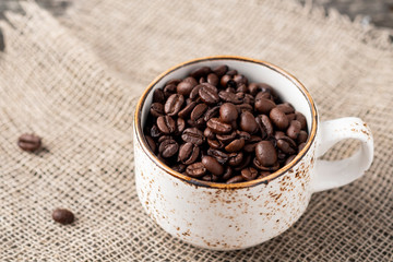 Cup with coffee beans.  Full cup with roasted coffee beans