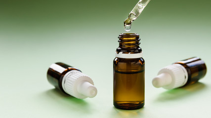 cosmetology, skin care, a row of glass bottles with pipettes and hyaluronic acid inside on a green...