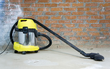  yellow construction vacuum cleaner on brick wall background